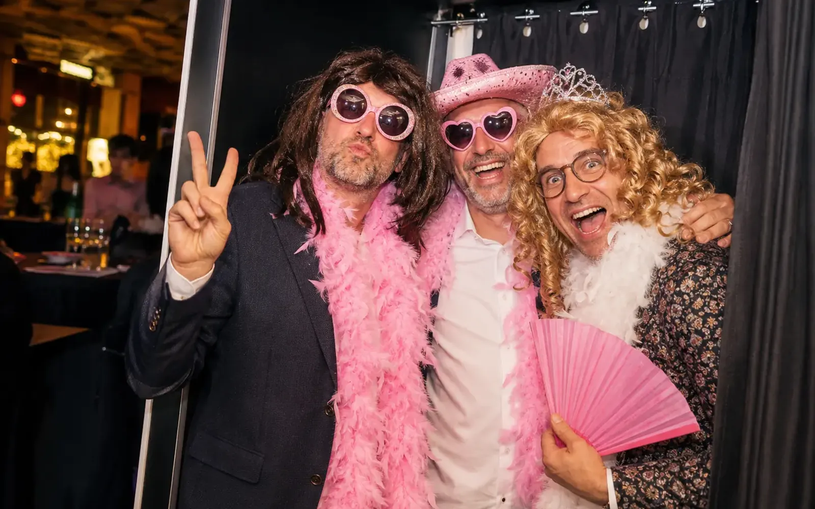 Drei Kollegen posieren verkleidet in einer Photobooth