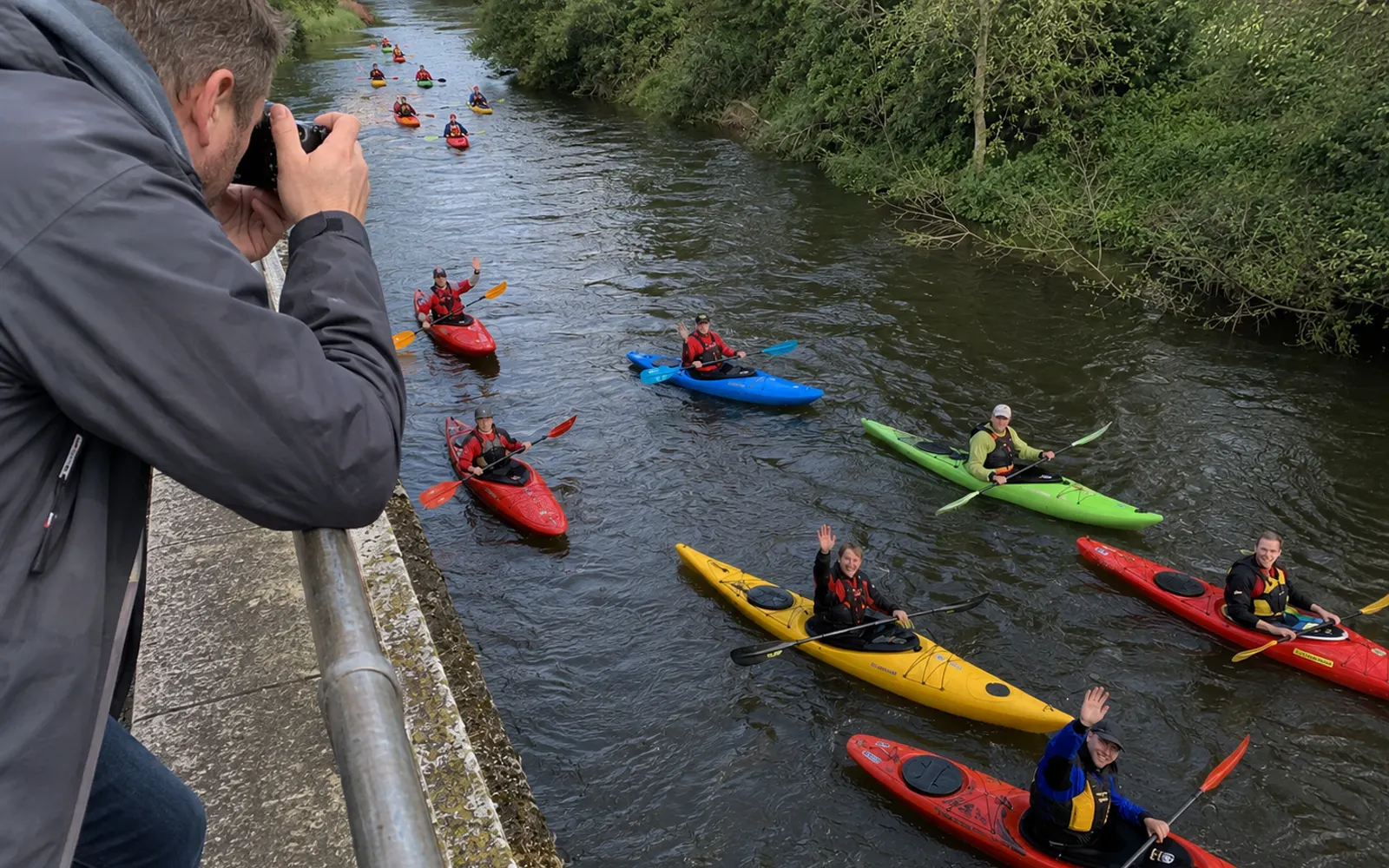 Fotograf fotografiert eine Gruppe Kajakfahrer von einer Brücke